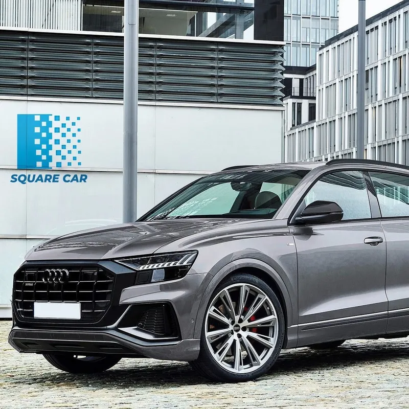 Audi Q8 grise devant un immeuble de bureaux, logo Square Car sur le mur